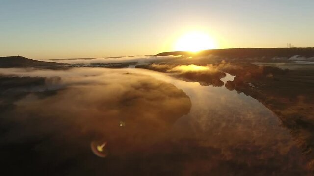 River valley bent early morning fog Primorye, Vladivostok. Assent from cloud to yellow orange sunrise horizon. Wide open space Aerial drone beautiful Russian nature landscape. Romantic cinematic mood.