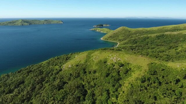 Vitiaz blue bay Gamova peninsula. Beautiful Russian nature. Summer sunny day. Forward flight above hill to sea ocean wide panorama. Aerial drone 4k footage