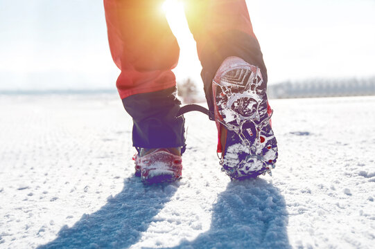 View Of Walking On Snow With Snow Shoes And Shoe Spikes In Winter.