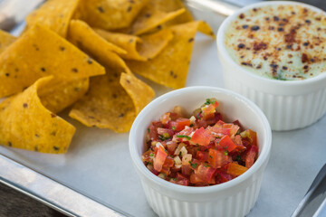Salsa sauce with nacho chips and baked spinach with cheese