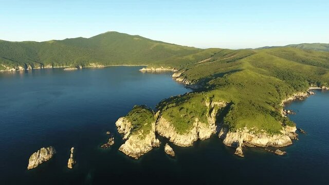 Cinematic gimbal flight from ocean to hills. Far East Marine Reserve, Primorsky Krai Vladivostok Russia. Unique National park Japan Sea. Aerial Helicopter Drone. Early morning yellow sun. 4k