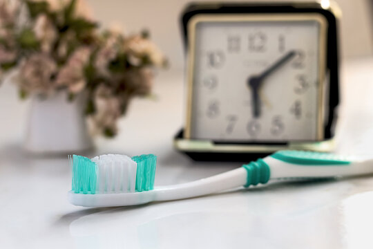 Closeup Of New Toothbrush And Clock In The Bathroom.