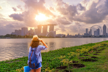 Young woman traveler  with singapore city downtown background - obrazy, fototapety, plakaty