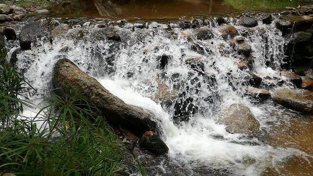 Slow motion rushing waterfall in the mountains with tropical forest. Beautiful nature background. 