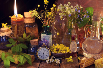 Natural still life with candle, bottles, healing herbs and flowers.