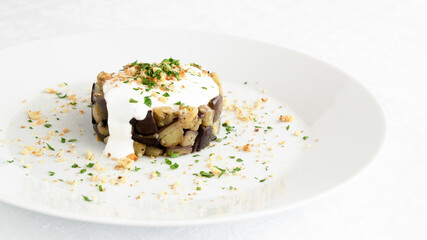 warm salad with spicy fried brinjal dressed with yogurt and sprinkled with grounded roasted walnut and finly chopped parsley 