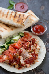 Close-up of roasted chicken with fresh vegetables and sauces served on lavash, selective focus