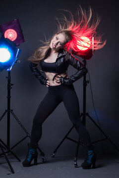 Girl in a leather jacket on stage and colored spotlights