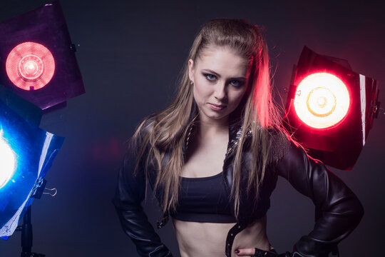 Girl in a leather jacket on stage and colored spotlights