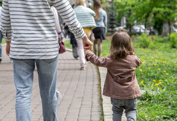 Fototapeta premium a little girl goes hand in hand with mom