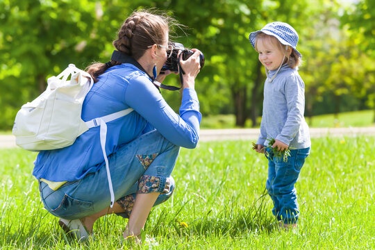 Mom takes pictures of a child in the park in summer