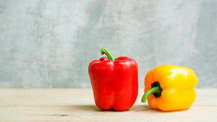 Red and yellow bell pepper on a wooden table.