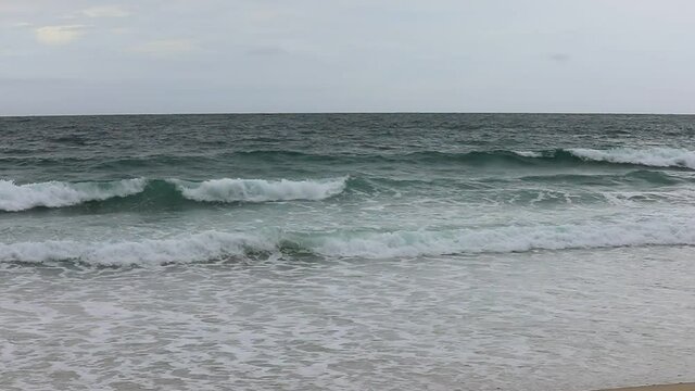 Sea waves on the beach in cloudy weather - slow motion