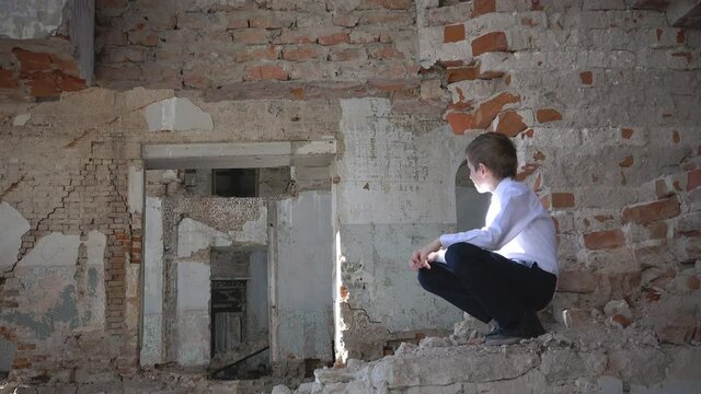 An orphan boy, a schoolboy sad in a ruined building after the war, lost, fear, loneliness
