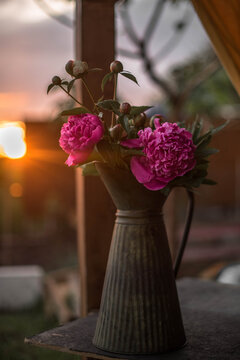 Peonies in an iron vase against a beautiful sunset