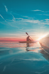 side view on kayak with another kayaker in the sunset