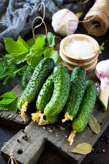 Homemade canned vegetables. Preservation of fresh and pickled cucumbers, garlic and spices on the kitchen table.