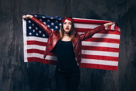 Girl with USA flag behind the back on dark background. Patriot, national event celebration, pride, usa citizen concept