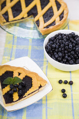 Piece of a blueberry pie and fresh berries on a wooden table.