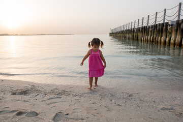 Little girl playing at the beach at sunset