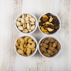 Four bowls with nuts on a  wooden table.