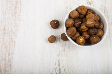 Hazelnut in a white bowl on a wooden table close up.