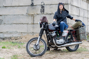Fototapeta na wymiar A post apocalyptic woman on motorcycle near the destroyed building