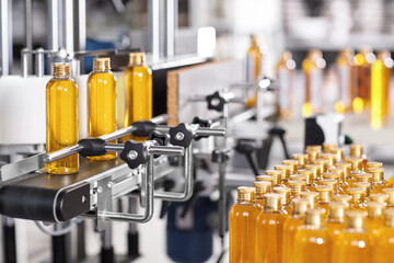 Production line of beauty and healthcare products at plant or factory. Process of manufacturing and packaging cosmetics goods. Glass or plastic bottles with screw caps standing on conveyor belt - obrazy, fototapety, plakaty