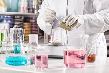 Equipped doctor making dermatology products in laboratory. Researcher wearing white gown and gloves...