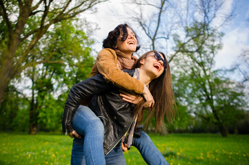 Fototapeta premium Two cute young women cheerfully spend time in the spring park