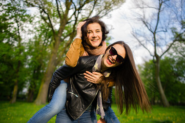 Two cute young women cheerfully spend time in the spring park