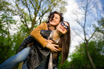 Two cute young women cheerfully spend time in the spring park
