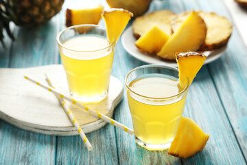 Glasses of pineapple juice on a blue wooden table