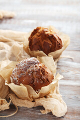 Tasty muffins with gauze fabric on wooden table