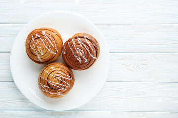Cinnamon buns in plate on wooden table
