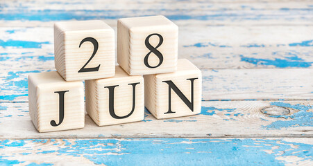 June 28th. Wooden cubes with date of 28 June on old blue wooden background.