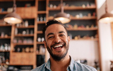 Happy young man laughing in a cafe