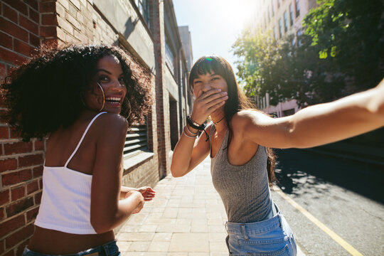 Female friends walking on street and having fun