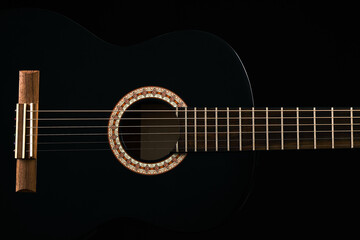 Fototapeta na wymiar A black Six-string classical acoustic guitar isolated on black background.