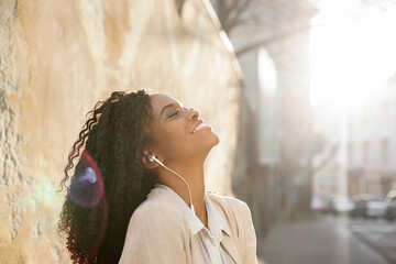 Beautiful black woman posing for ca,era with her head raised to the sky. Woman has headphones.