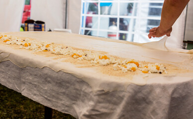 Homemade strudel dough on a traditional linen tablecloth ready for making cottage cheese pie and...