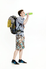 Young tourist with  backpack drinking water on white background