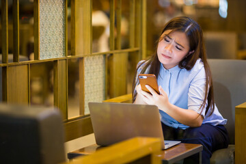 Woman using smartphone in night time at cafe feel upset