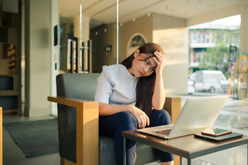 Asian woman using laptop and she has headache in cafe