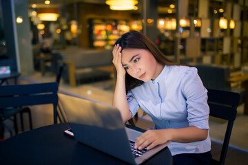 Woman  using laptop in night time at cafe  she feel worried