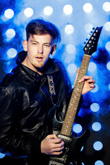Obraz premium young attractive rock musician playing electric guitar and singing. Rock star on background of spotlights