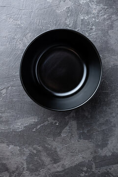 Empty black soup plate on dark grey background, top view