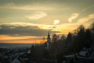 Ausblick auf Dorf mit Kirchturm bei Sonnenuntergang