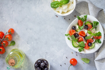 Greek salad with arugula, tomatoes, feta cheese, onions, cucumber and olives, seasoned with oil. Vitamin snack on the festive table. Top view.