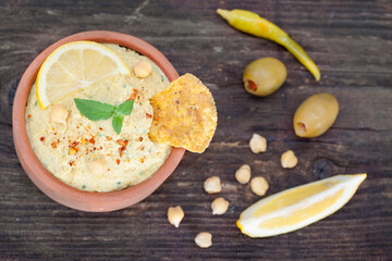 Fototapeta na wymiar Vegetarian Humus with sesame seeds,tortilla chip, olives and lemon. Top view.